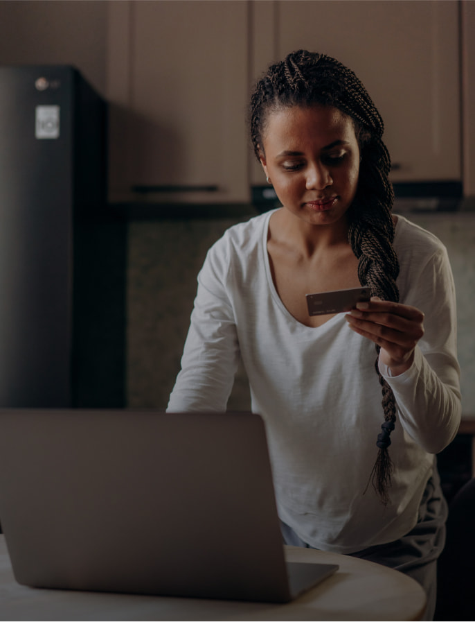 Woman holding a Netspend card in front of a computer