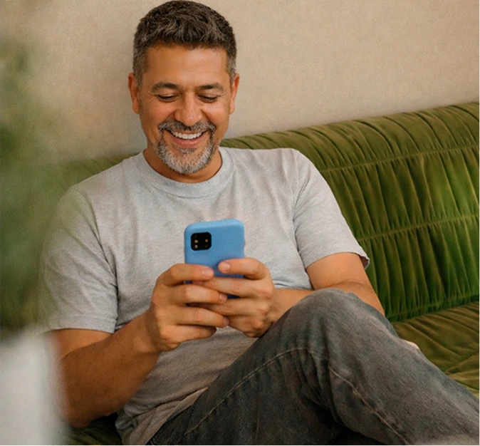 Man on couch smiling while looking at his phone