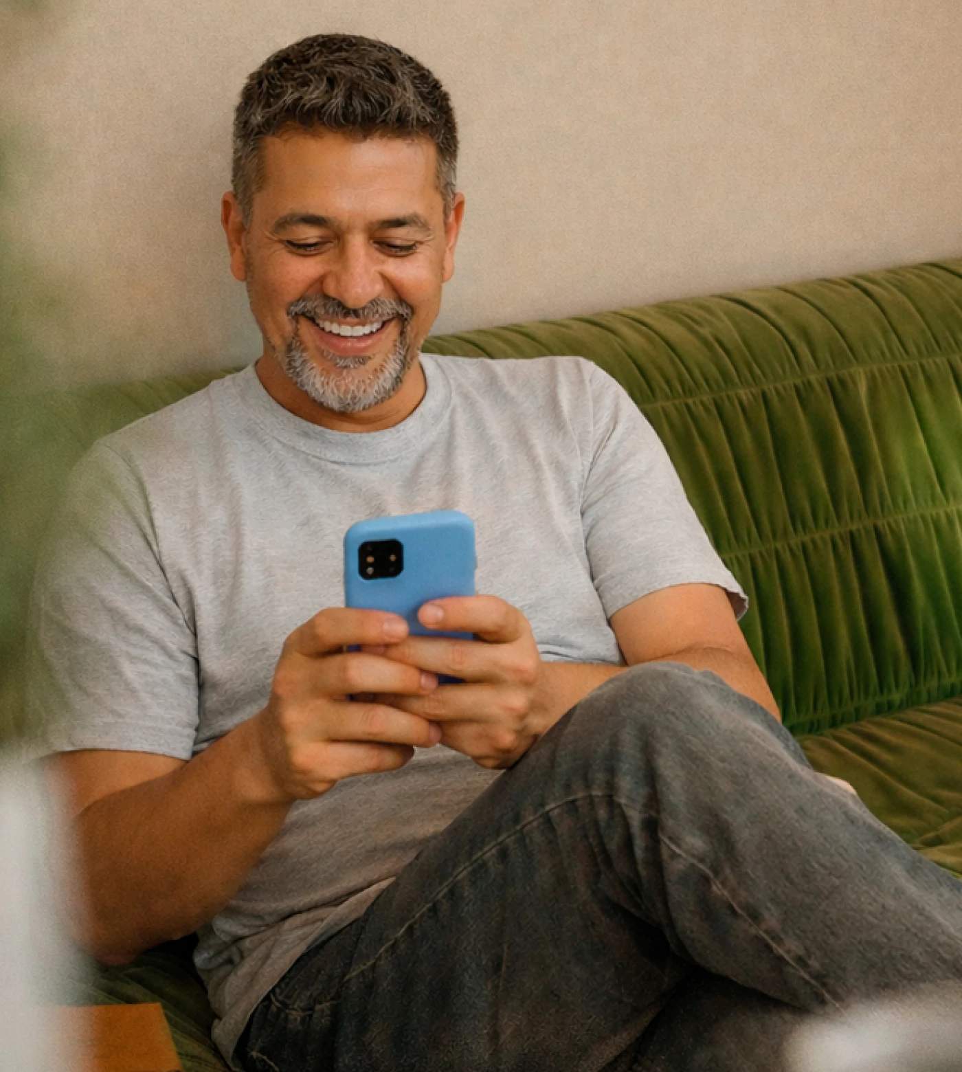 Man on couch smiling while looking at his phone